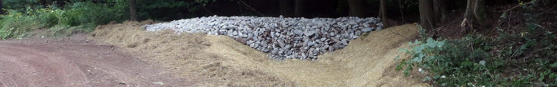 A dirt road with straw and gravel along the sides for erosion control