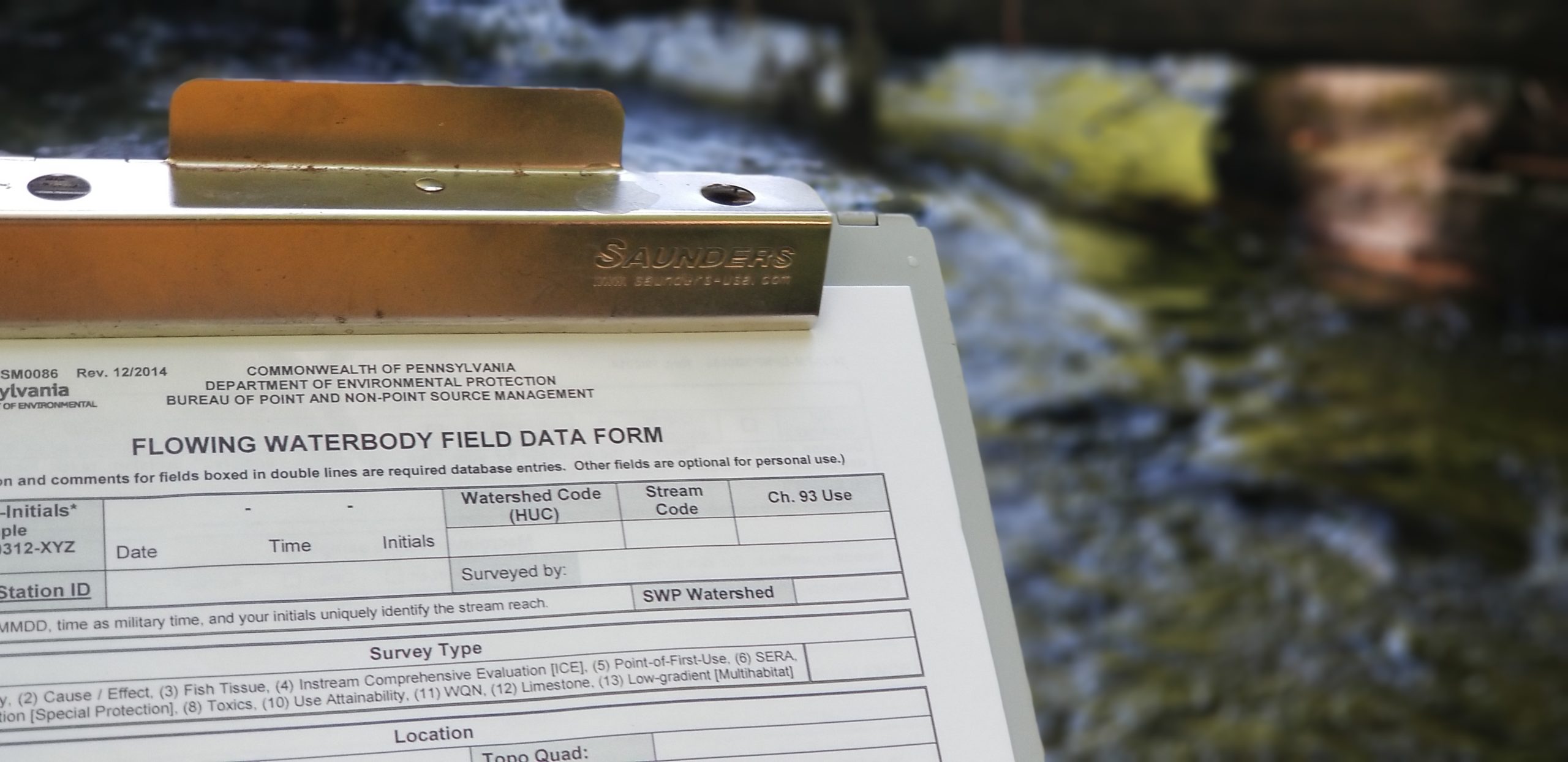 A closeup of a clipboard holding a form titled "Flowing Waterbody Field Data Form"