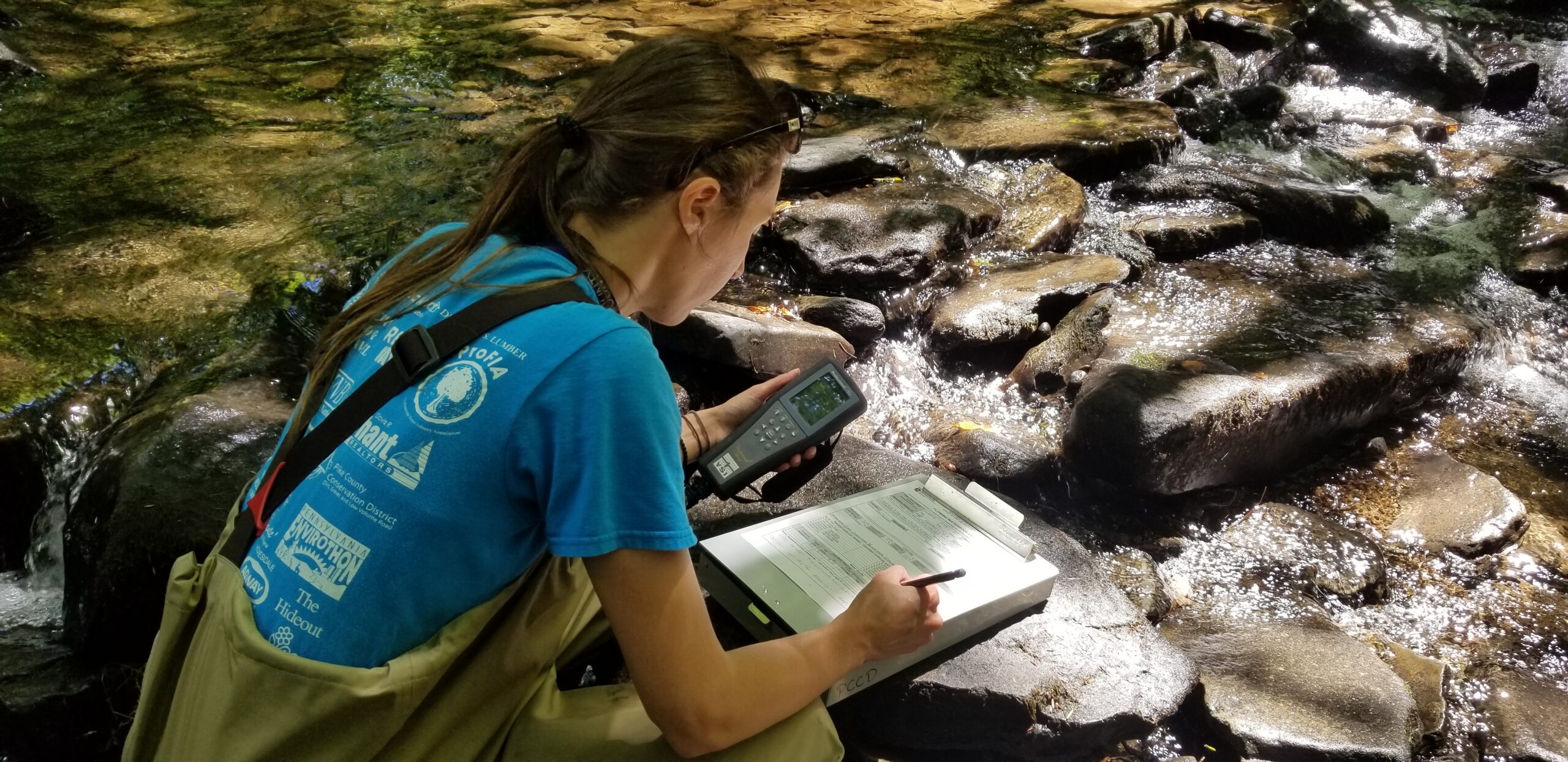 An image of Rachel Posavetz, watershed specialist, filling out a data sheet in the stream