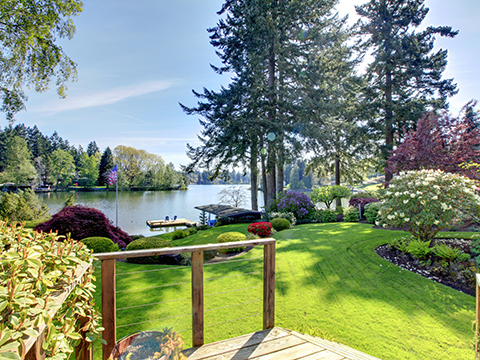 Landscaped yard on a lakefront with flowers, trees, and grass
