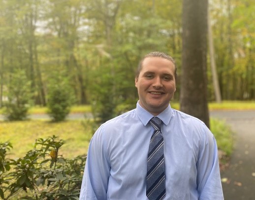 Resource Conservationist Brandon poses for a headshot next to a rhododendron