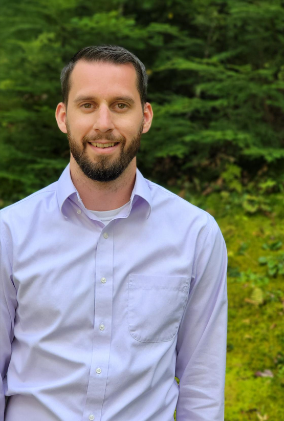 District Engineer poses in front of evergreen trees