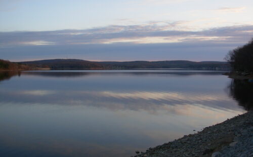 A lake at dusk, taken from a gravel beach