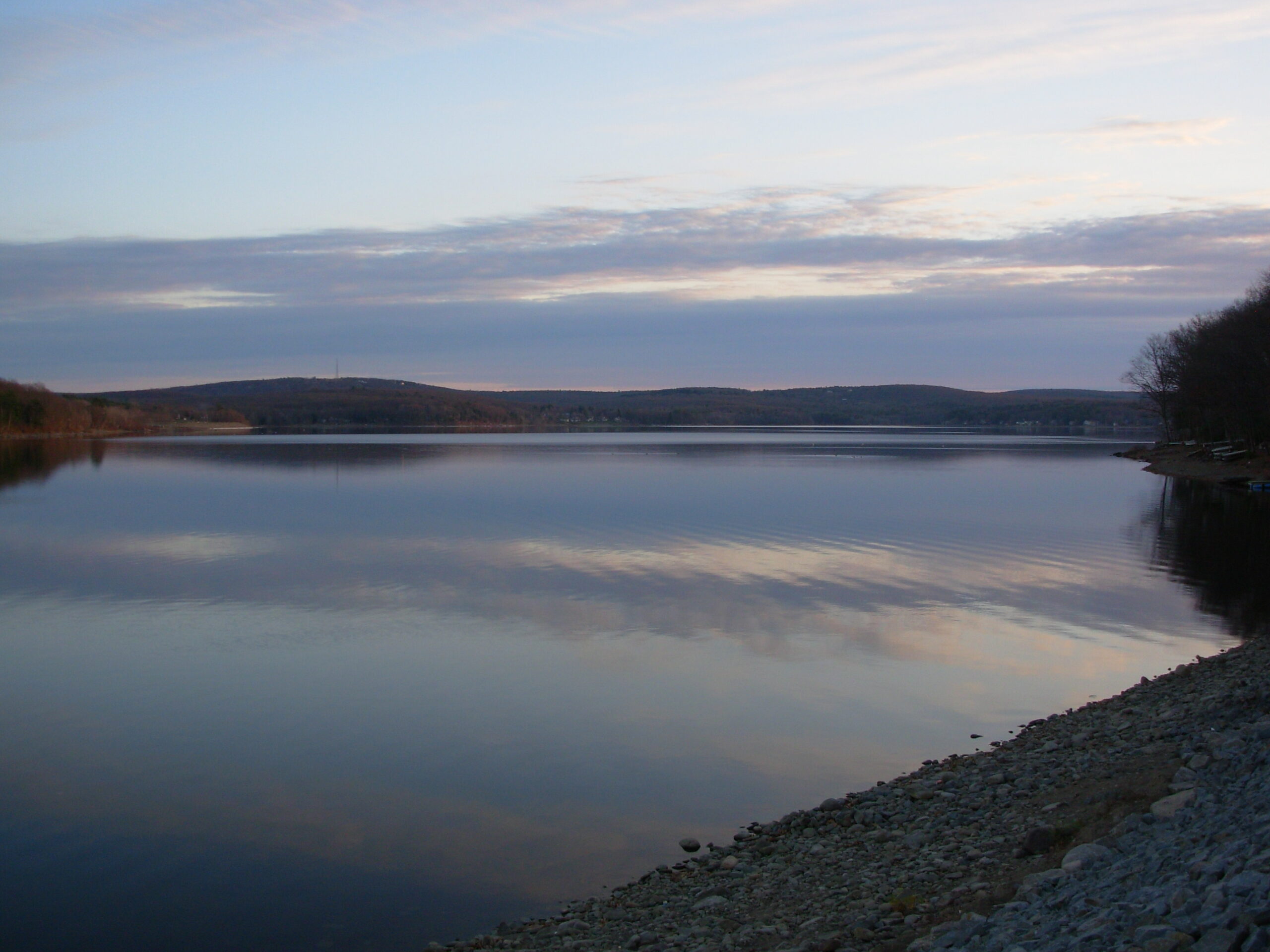 A lake at dusk, taken from a gravel beach