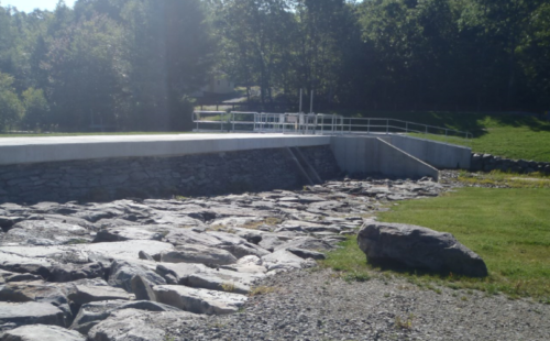 A dam surrounded by large rocks and a lawn