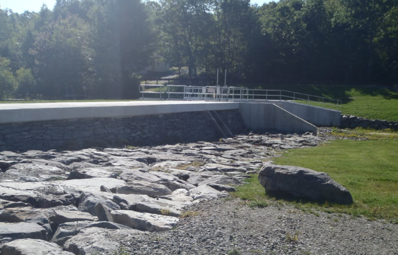 A dam surrounded by large rocks and a lawn