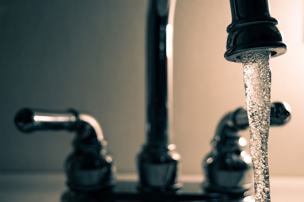 Close up of a sink faucet with water coming out