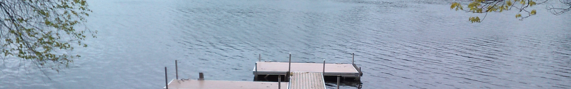 A dock in a lake with fall foliage handing down on either side above it