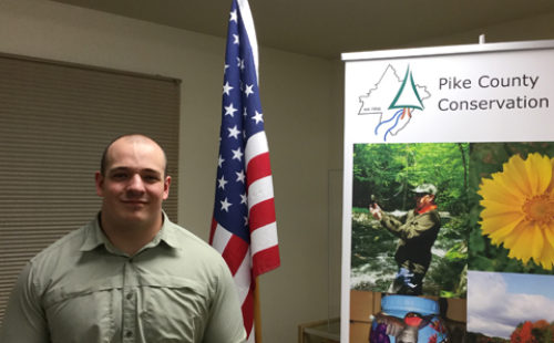 Pike County Conservation District's new Resource Conservationist standing next to a PCCD banner