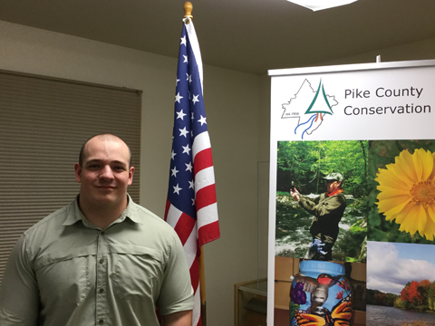 Pike County Conservation District's new Resource Conservationist standing next to a PCCD banner