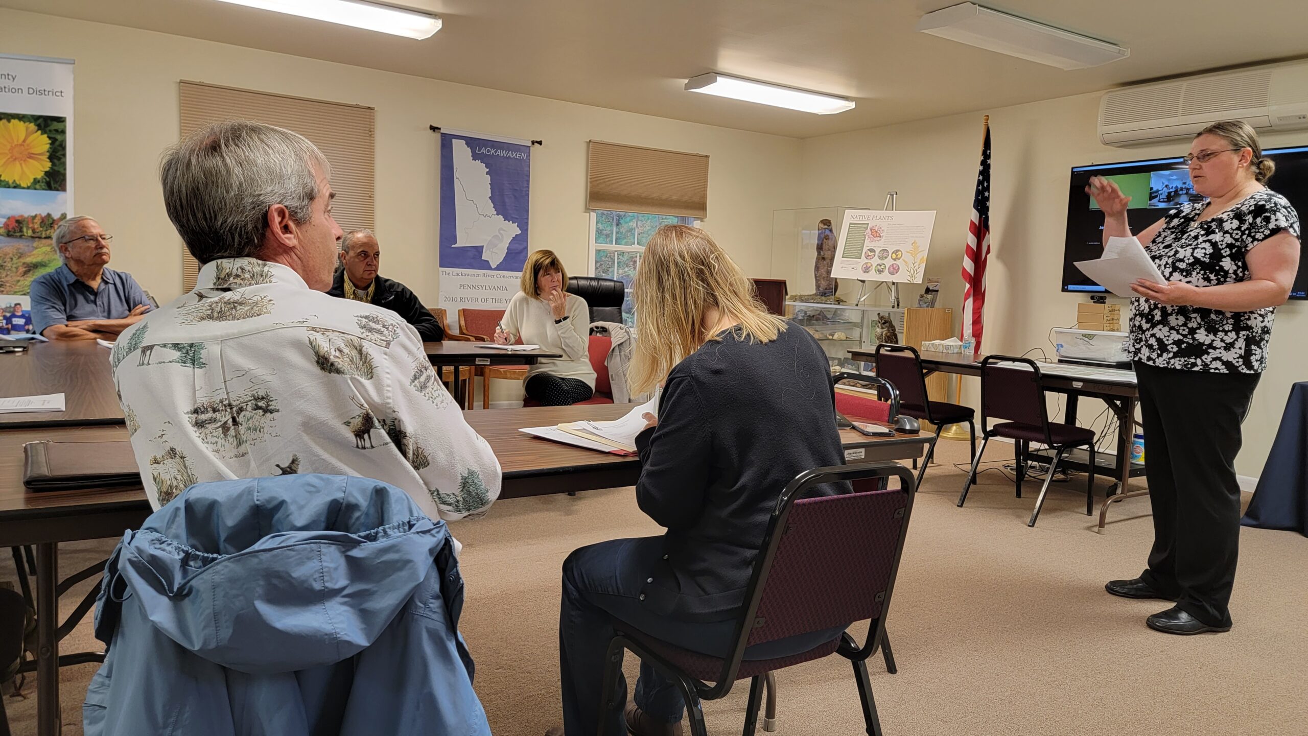 Board meeting in progress with one staff member presenting and others seated at a table