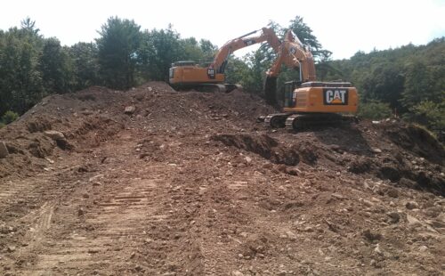 Two excavators digging on a mound of soil
