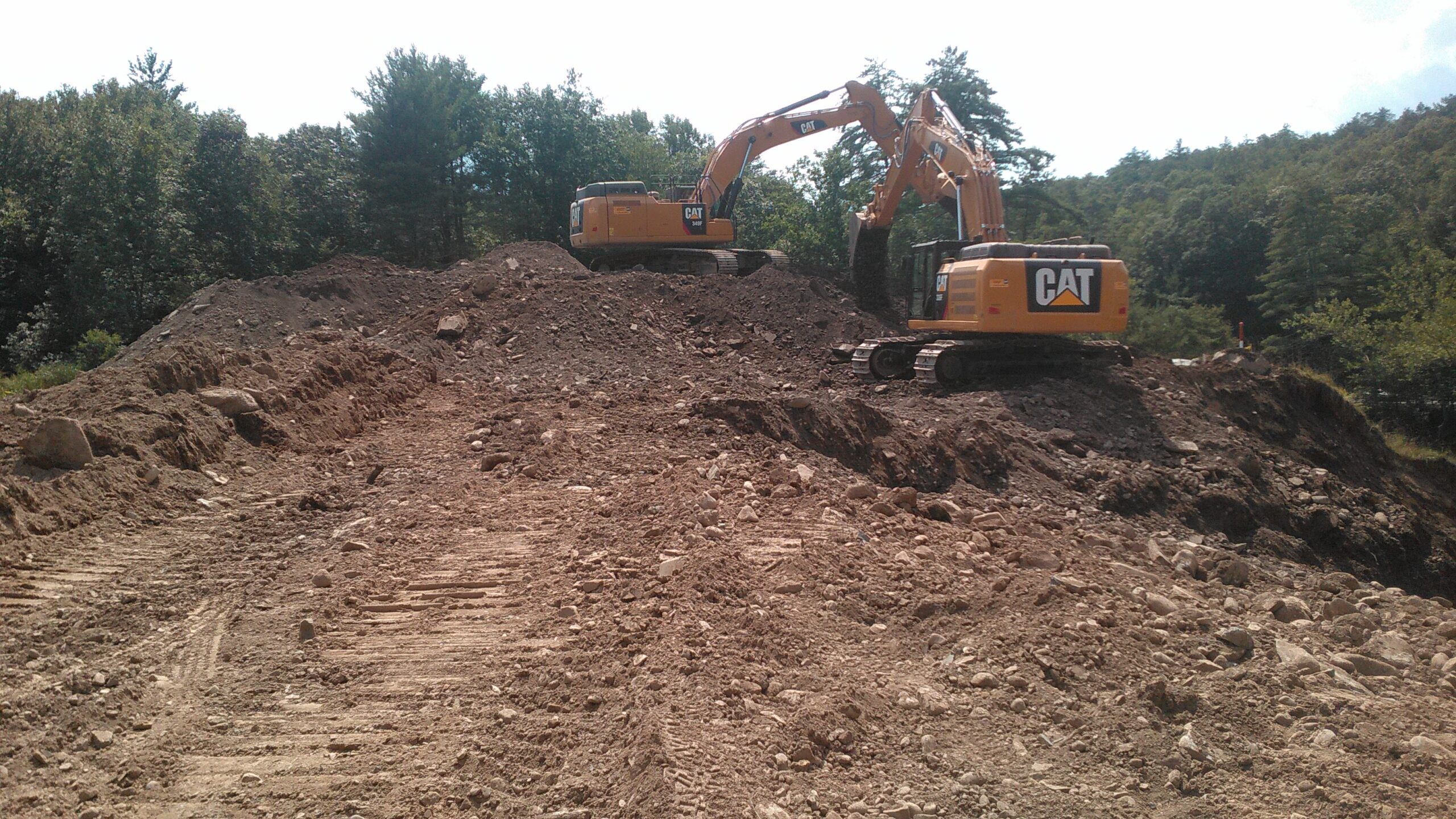 Two excavators digging on a mound of soil