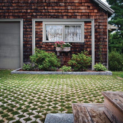 Driveway in front of a house, pavers have grass growing between them