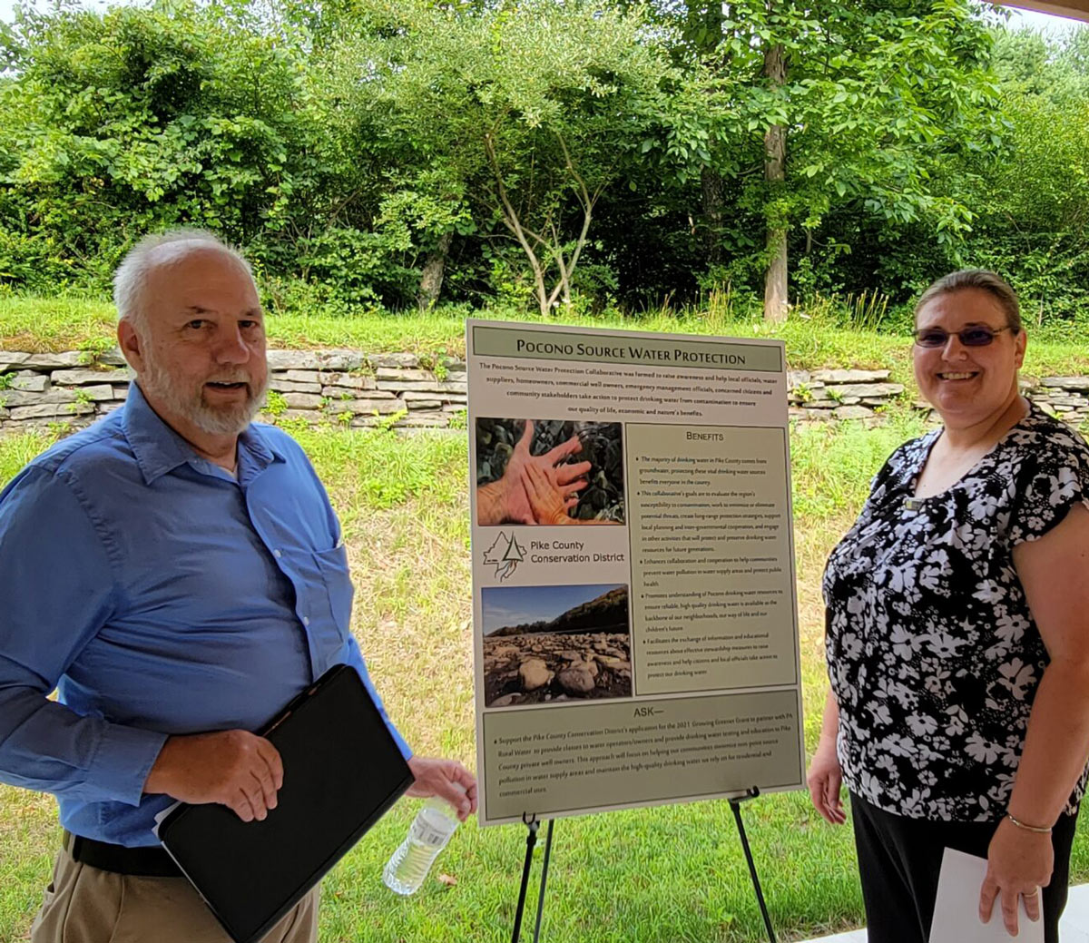 Staff and board member pose with a Pocono Source Water Protection Collaborative poster