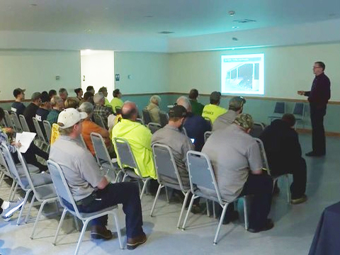 PCCD's Road Maintenance Workshop, a group of people seated and listening to a presenter standing at a projected image