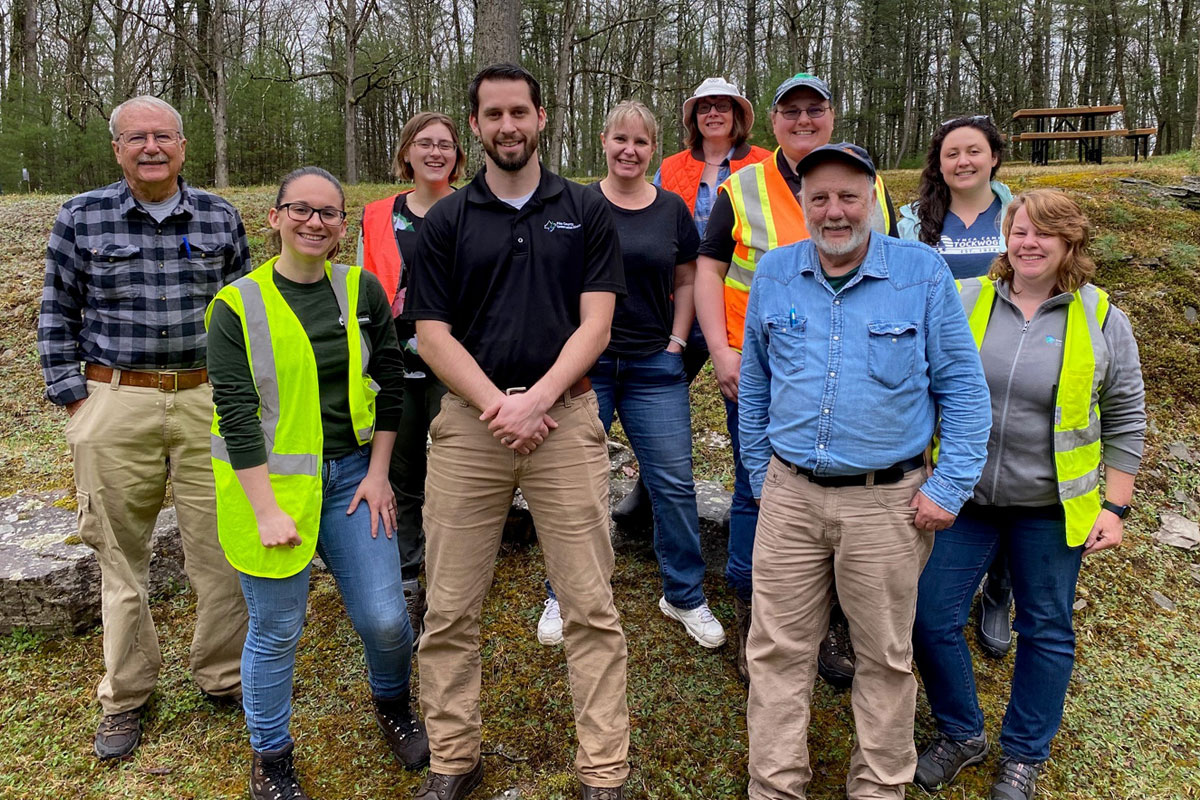 Group of staff, board members, and partners posing for a photo outside wearing safety vests