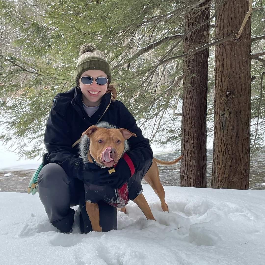 Tara kneeling in the snow with her dog