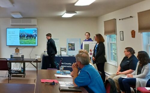 Two students give a presentation at a conservation district board meeting about their environmental education grant project