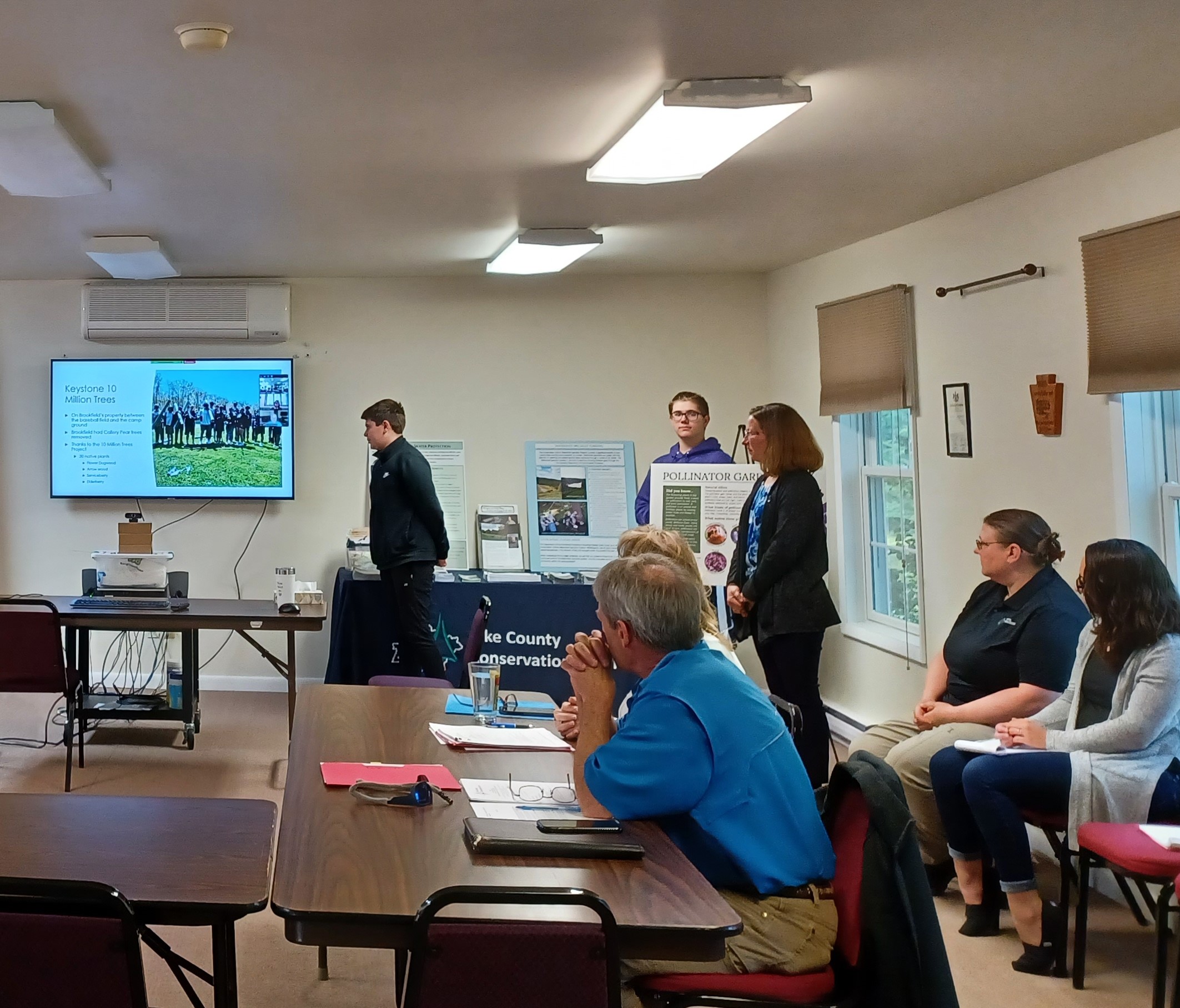 Two students give a presentation at a conservation district board meeting about their environmental education grant project