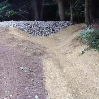 A dirt road with straw and gravel along the sides for erosion control