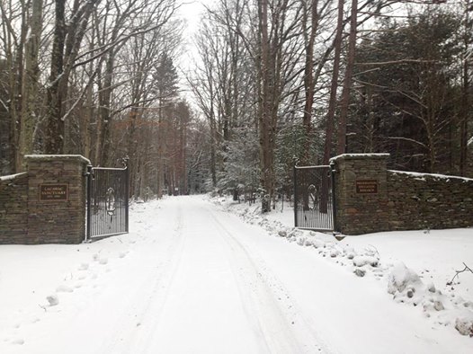 A snowy road leading through an open stone gate