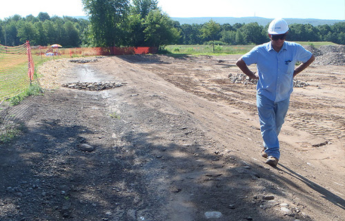A staff member inspecting an earth disturbance site with exposed sediment