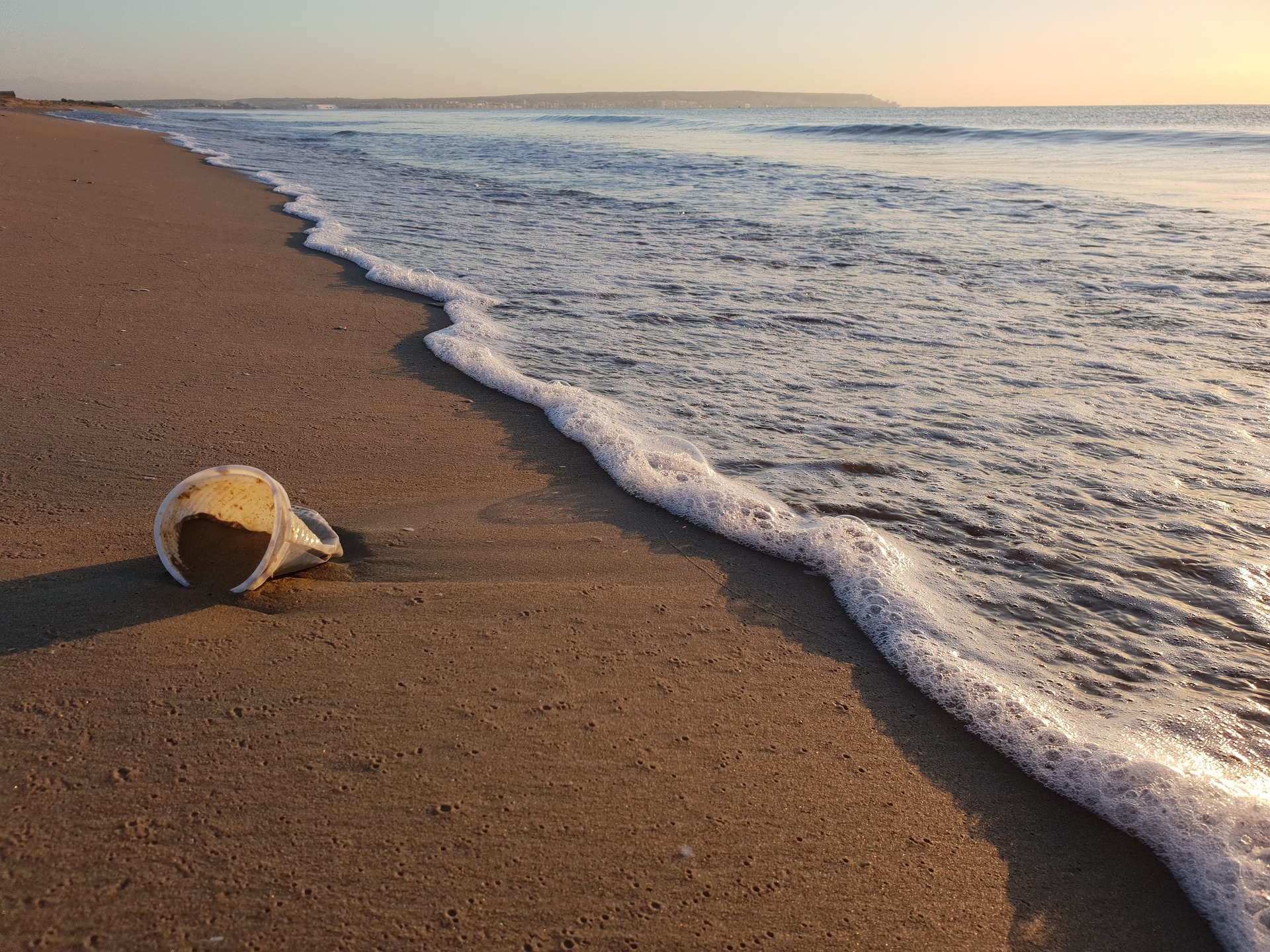 A plastic cup in the sand on the beach