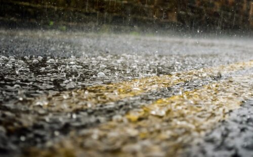 Close up of rain drops falling on a paved road