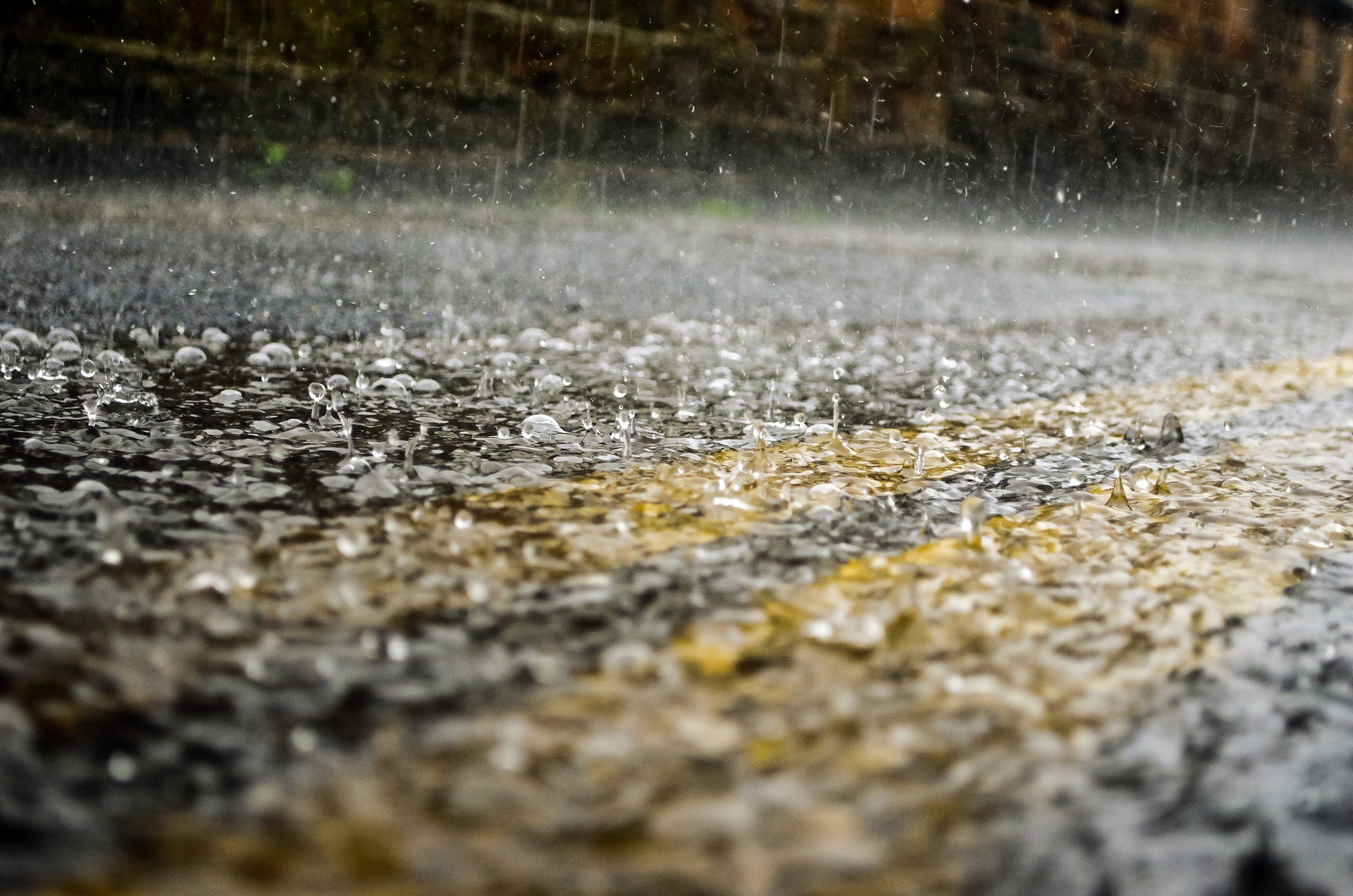 Close up of rain drops falling on a paved road