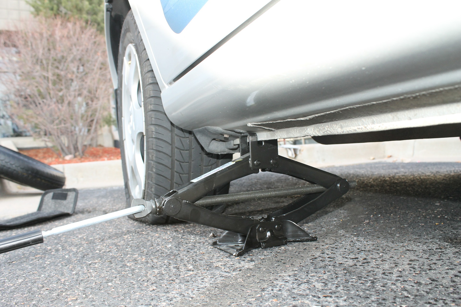 closeup of a jack holding up a car with a flat tire