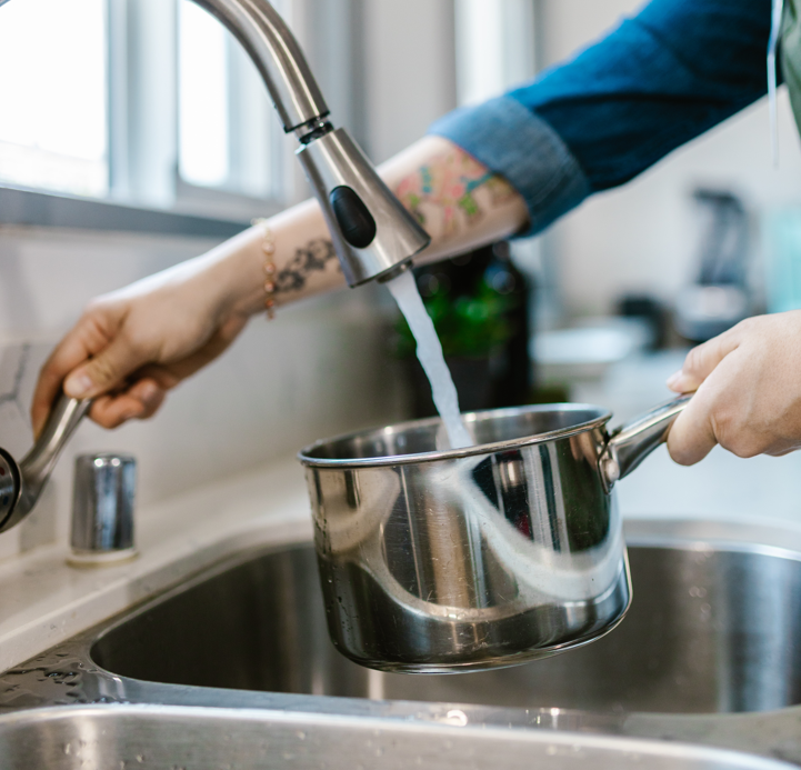 A person fills a saucepan at a faucet